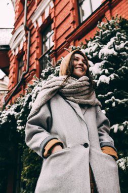 Kırmızı bina boyunca yürüyen genç kadın sıcak giyinmiş 