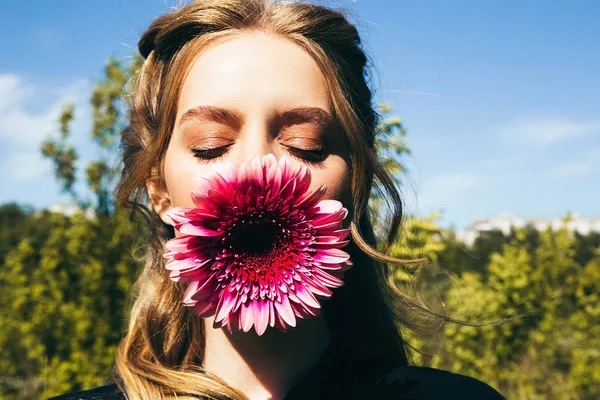 Ağzında mor gerbera ile genç kadın portresi