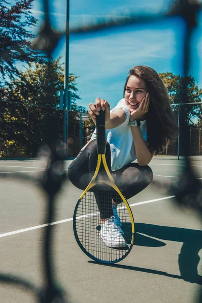 Tenis kortunda tenis raketiyle poz veren sportif genç kadın