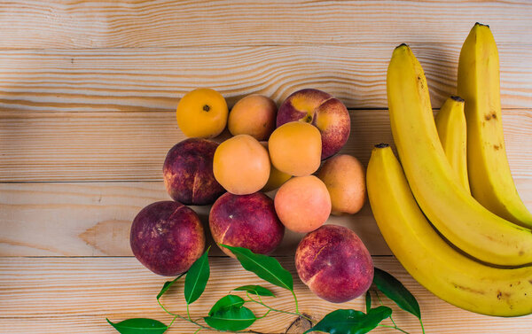 bananas, peaches, apricots, wooden background, space for text, wood texture