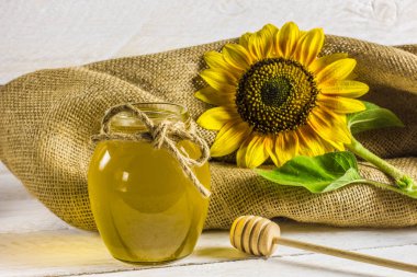 mayıs bal ve tahta üzerinde tahta bir tahta kaşık ile kavanoz, çantanın arka plan üzerinde ayçiçeği ve bal