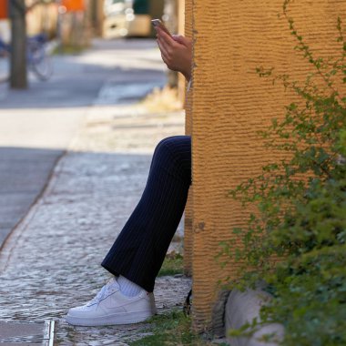 Berlin, Almanya 07 Haziran 2018: bir adım de Berlin üzerinde oturan ve Smartphone'da yazarak genç kadın