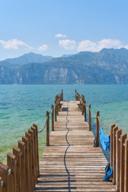 Malcesine 'deki Garda Gölü kıyısında, batı kıyısındaki Alpler manzaralı bir iskele.                               