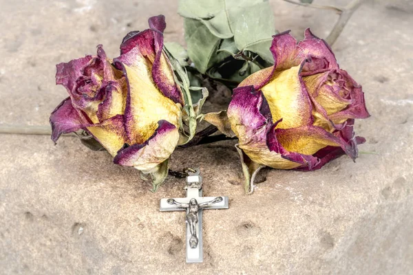 Christelijk kruis op rozenkrans en een droge gele rode rozen liggen op een zandsteen — Stockfoto