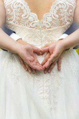 Dört el bir gelinliğin sırtında bir kalp oluşturur.