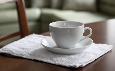 Boş bir beyaz fincan ve bir fincan tabağı üzerinde ahşap bir masa standı