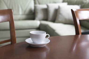 Boş bir beyaz fincan ve bir fincan tabağı üzerinde ahşap bir masa standı