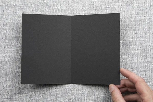 Męskie ręce trzymając pusty czarny broszury — Zdjęcie stockowe