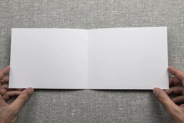 Mens hands holding empty white booklet — Stock Photo, Image