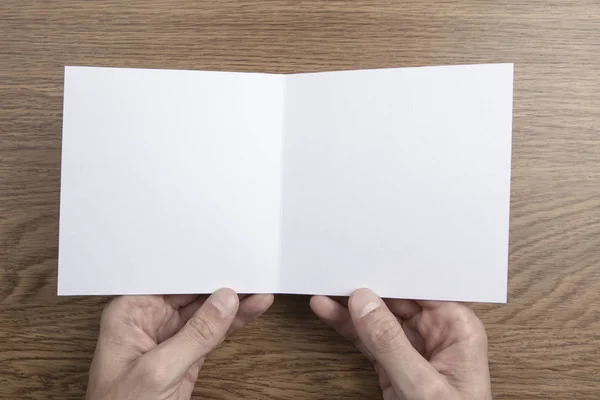 Mens hands holding white booklet — Stock Photo, Image