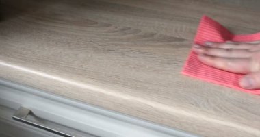 Kahverengi ahşap bir masa pembe bir bez ile silerek bir erkek el Close-Up