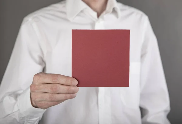 En man som innehar röd Obs papper — Stockfoto