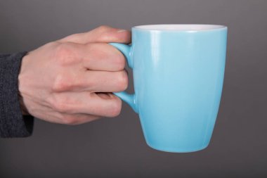 Elinde mavi kupa tutan bir adam.