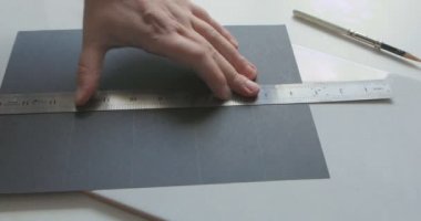 Erkek elin zaman atlamalı bir kalem ve kağıt levha üzerinde metal bir cetvel ile bir çizim yapar