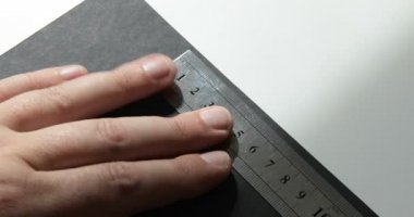 Erkek elin zaman atlamalı bir kalem ve kağıt levha üzerinde metal bir cetvel ile bir çizim yapar