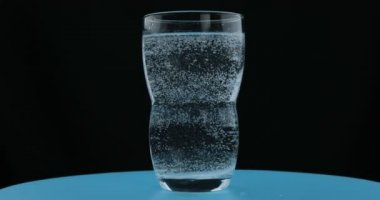 Maden suyundan kabarcıklar, siyah arka plan üzerinde bir bardak soda