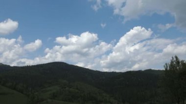 Dağların tepesinde bulutlarla mavi gökyüzünün zaman atlaması