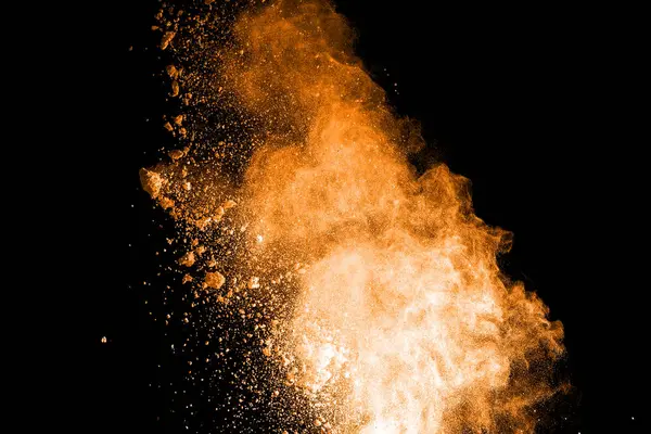 Turuncu ve kahverengi toz siyah arka plan üzerinde patlama.