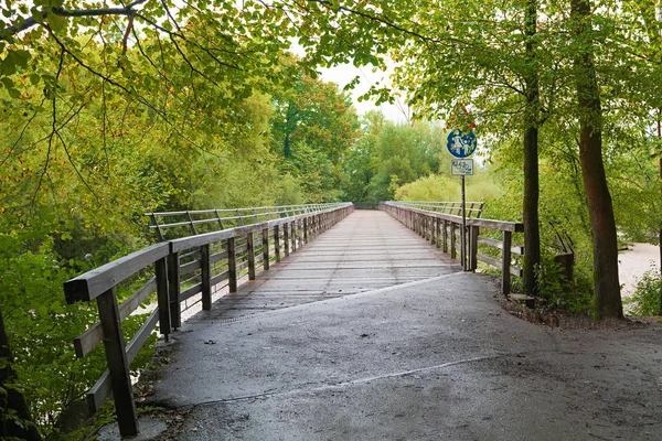 Idyllic walkway over isar river bridge munich amongst green bran — Stock Photo, Image