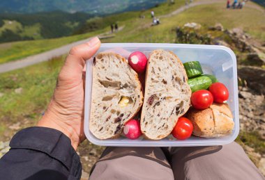Brotzeit kutusunu tutan adam, dağlarda öğle yemeği