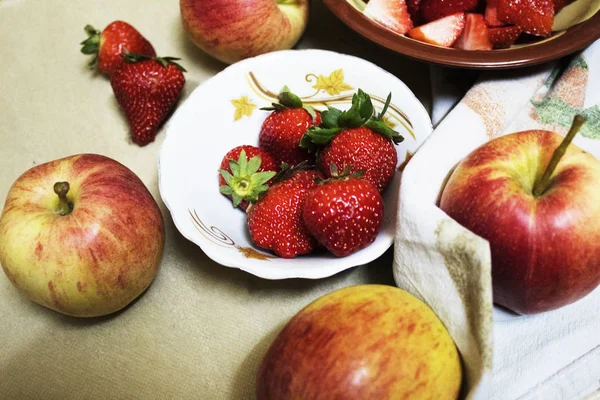 Fresh strawberries and apples on table.