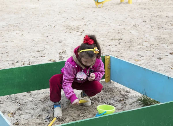 Small active girl plaing with sand.
