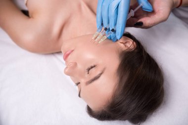 Güzellik enjeksiyon. Doktor eller kadın yüzü yakınındaki şırınga closeup. Yüz cilt tedavi kaldırma aldıktan güzel kadın portresi.