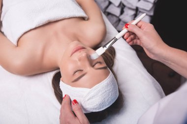 Saçlı çarpıcı genç kadın beyaz banyo bornoz giymiş temiz cilt çıplak omuz arkasında, sabit ve saç sarma kozmetik prosedür, yapıyor, mikrodermabrazyon, kapatın