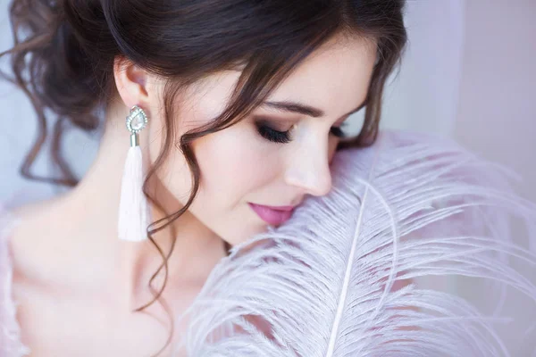 Face and body skin care concept. Young beautiful woman, close-up portrait with large white feather near face