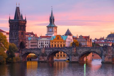 Eski kasaba binalarının ve Charles Köprüsü 'nün güzel manzarası, önlerinde kuğular, Çek Cumhuriyeti Prag' ta, Vltava nehri boyunca gün batımında