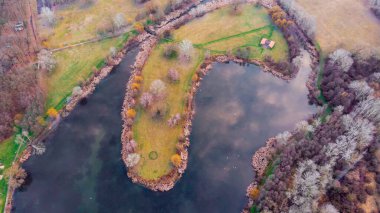 Macaristan, Avrupa 'da bir adada gölün ortasında güzel renkleri olan rahat bir gölün insansız hava aracı görüntüsü.