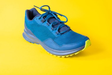 Mavi antrenman ayakkabıları sarı arka planda hafif ve rahattır.