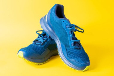 Mavi antrenman ayakkabıları sarı arka planda hafif ve rahattır.