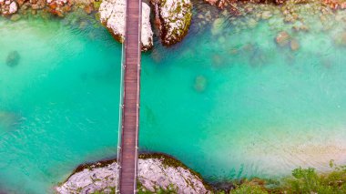 Slovenya 'daki Julian Alpleri' nde Bovec yakınlarındaki turkuaz mavi Soca nehri (Isonzo) ve ahşap köprü havadan görülüyor.