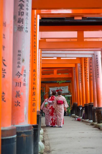Chica japonesa en vestido de kimono caminar y ver torii rojo en Fushimi Inari-taisha santuario —  Fotos de Stock