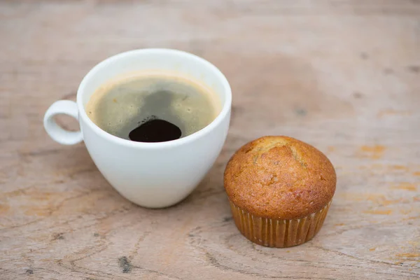 Bolo de xícara de banana e café preto na mesa de madeira — Fotografia de Stock