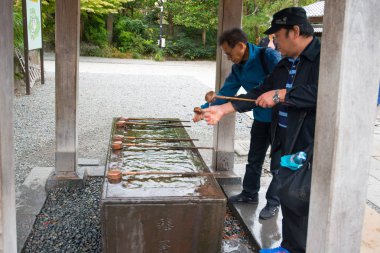 Kamakura, Japonya 'daki Kotoku-in tapınağının önünde insanlar el ve ağızlarını yıkıyor.