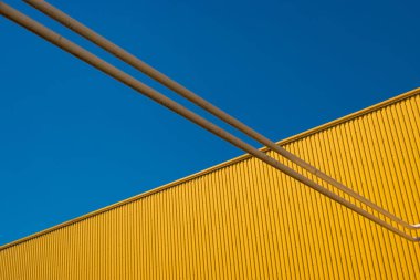 Minimalist bir sarı duvar ve iki boru gökyüzü kesme parçalara çerçeveyi böler