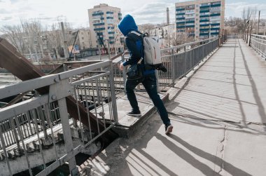 Yalnız ve mutsuz men bir Demiryolu Köprüsü'nde beyaz çanta ile. Güneşli gün.