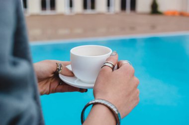 bir kızın elini bir mavi su havuzu arka plan karşı çay