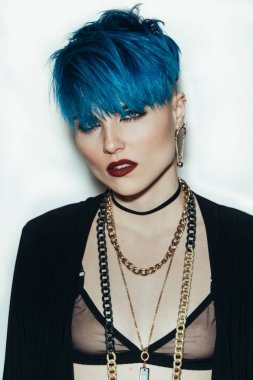 moda fotoğrafçılığı doğruca kameraya bakarak beyaz zemin üzerine mavi saçlı kız. Kalın sarı zincir ve boynundaki bijouterieher. Profesyonel model Studio poz