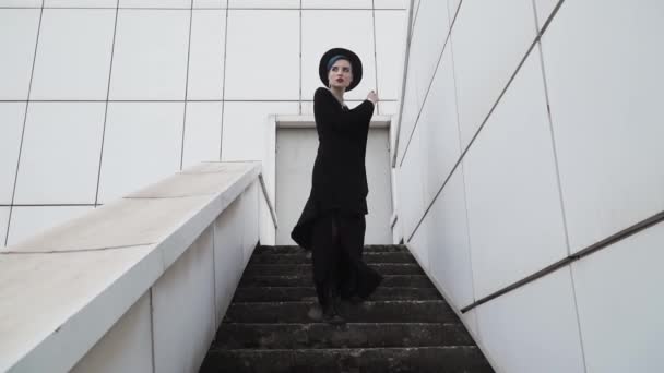 Girl Black Tunic Cloak Hat Goes Stairs Background White Minimalistic — Stock Video