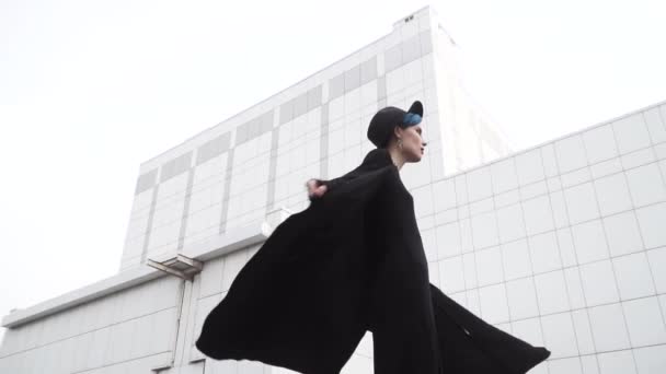 Girl Black Tunic Cloak Hat Turns Front White Minimalistic Building — Stock Video