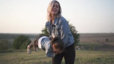 Karışık yarış Aile, Avrupa anne ve vakit parkta günbatımı üzerinde Çinli kızı. Mutlu anne çocuğunu tutan ve eğlenceli Park etrafında dön. Bahar ya da yaz sezonu sıcak. Ağır çekim vurdu