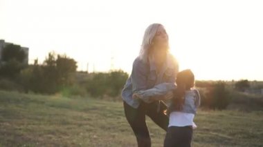Karışık yarış Aile, Avrupa anne ve vakit parkta günbatımı üzerinde Çinli kızı. Mutlu anne çocuğunu tutan ve eğlenceli Park etrafında dön. Bahar ya da yaz sezonu sıcak. Ağır çekim vurdu