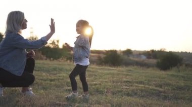 Yüksek beş Avrupa annesi ve çalışma düz için kameraya veren şirin küçük Çinli kız. Karışık yarış Aile, Avrupa anne ve Asyalı kızı vakit parkta sunset Bulvarında. Bahar ya da yaz sezonu sıcak. Ağır çekim vurdu
