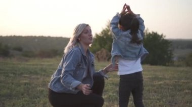Sevimli küçük Çinli kız heyecanlı atlama ve claping elleri. Karışık yarış Aile, Avrupa anne ve Asyalı kızı vakit parkta sunset Bulvarında. Bahar ya da yaz sezonu sıcak