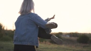 Karışık yarış Aile, Avrupa anne ve vakit parkta günbatımı üzerinde Çinli kızı. Mutlu anne çocuğunu tutan ve çevresinde park, kız predend eğlenceli uçan onun dön. Bahar ya da yaz sezonu sıcak.