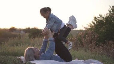 Karışık yarış Aile, Avrupa anne ve Asyalı kızı vakit parkta sunset Bulvarında. Yerde yatan ve gülümseyen oynuyorlar. Anne kızı onun kucağına alır. Bahar ya da yaz sezonu sıcak