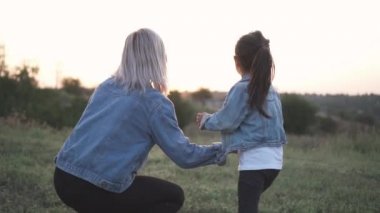 Karışık yarış Aile, Avrupa anne ve Asyalı kızı parkta vakit. Anne kızına ne kadar güzel gün batımını olduğunu gösterir. Her ikisi de frpm arkasında vurdu güneş bakmak. Bahar ya da yaz sezonu sıcak. B-roll slowmotion atış.